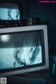 A woman is sitting in front of a television set.