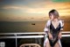 A woman in lingerie posing on a balcony overlooking the ocean.