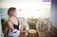 A woman sitting on a chair on a balcony overlooking the ocean.