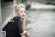 A woman leaning against a wall by the water.