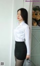 A woman in a white shirt and black skirt posing for a picture.