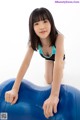 A young woman is sitting on a blue exercise ball.