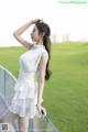 A woman in a white dress standing on a balcony.