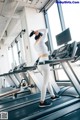 A woman is running on a treadmill in a gym.