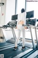 A woman is running on a treadmill in a gym.