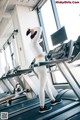 A woman is running on a treadmill in a gym.