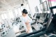 A woman is standing on a treadmill in a gym.