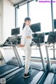 A woman standing on a treadmill in a gym.