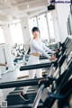 A woman is running on a treadmill in a gym.