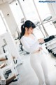 A woman in a white top and leggings standing in a gym.