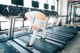 A woman is running on a treadmill in a gym.