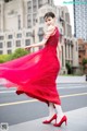 A woman in a red dress is dancing on the street.