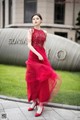 A woman in a red dress standing in front of a building.