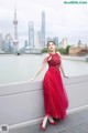 A woman in a red dress standing on a bridge.