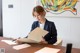 A woman sitting at a table writing on a piece of paper.