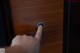 A person is pressing a button on a wooden door.