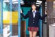 A woman in a school uniform standing in front of a door.