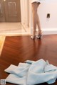 A woman in a white dress and high heels standing on a wooden floor.