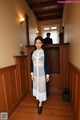 A woman standing in a hallway next to a wooden wall.