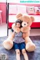 A girl sitting on the floor holding a large teddy bear.