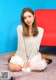 A woman sitting on the floor in front of a red couch.