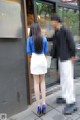 A woman in a blue shirt and white skirt is walking down the street.