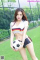 A woman holding a soccer ball on a field.