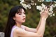 A woman holding a branch of a tree with white flowers.