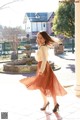 A woman in a white shirt and a brown skirt.