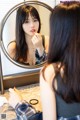 A woman applying lipstick in front of a mirror.