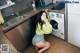 A woman sitting on the floor in front of a washing machine.