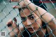 A woman behind a chain link fence looking at the camera.