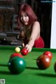 A woman in a red dress is playing snooker.