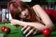 A woman laying on a pool table with red balls.