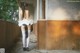 A woman in a white dress and black stockings standing in an abandoned building.