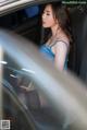 A woman in a blue dress sitting in a car.