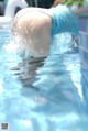 A woman in a blue dress is diving into a swimming pool.