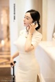 A woman in a white dress talking on a cell phone.