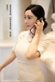 A woman in a white dress talking on a cell phone.