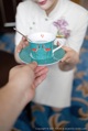 A woman holding a cup and saucer with a spoon in it.