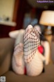 A woman in fishnet stockings is sitting on a couch.