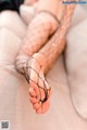 A woman in fishnet stockings is sitting on a couch.