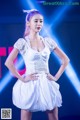 A woman in a white dress standing on a stage.