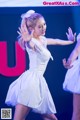 A woman in a white dress dancing on a stage.