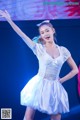 A woman in a white dress dancing on a stage.