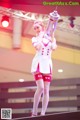 A woman in a white and pink outfit holding a gun.