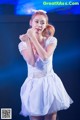 A woman in a white dress dancing on a stage.