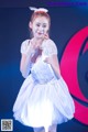 A woman in a white dress standing on a stage.