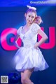 A woman in a white dress standing on a stage.