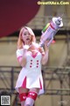 A woman in a white and pink outfit holding a toy gun.